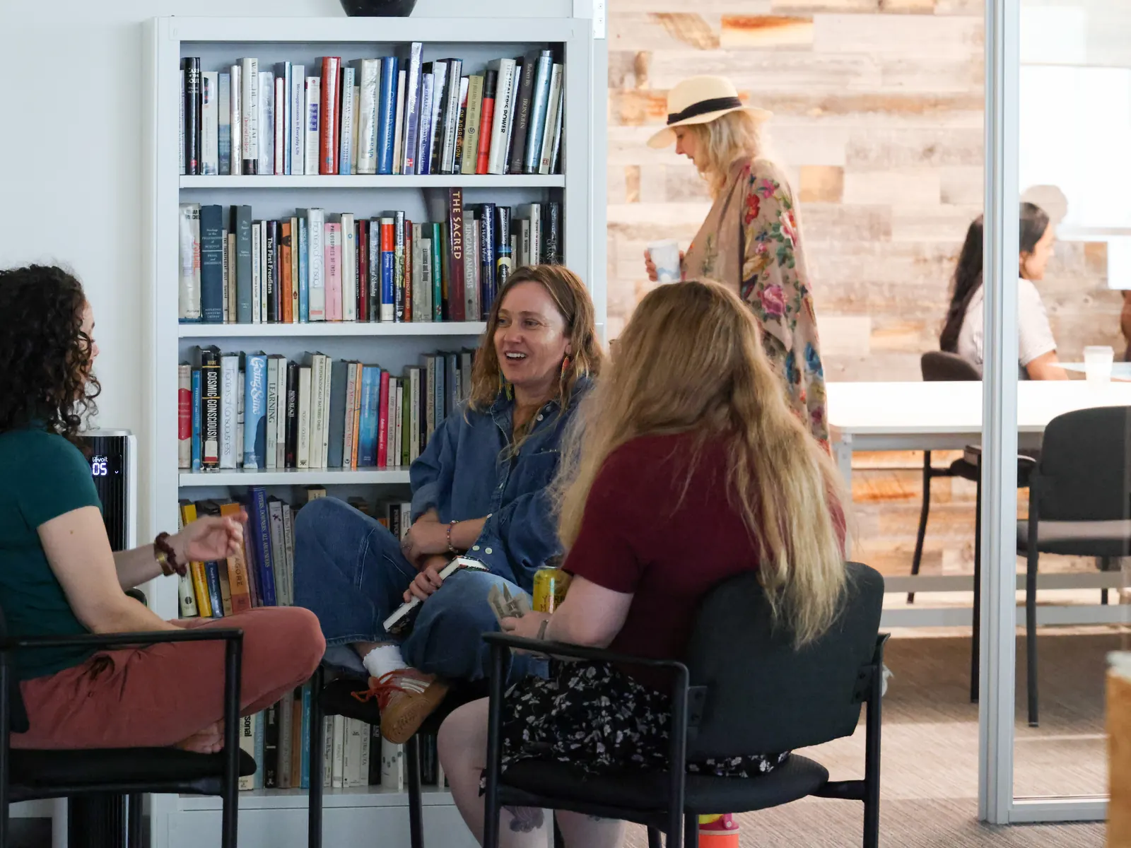 A small group talks in a circle of chairs by the bookshelves at a Meridian Transformative Learning Lab