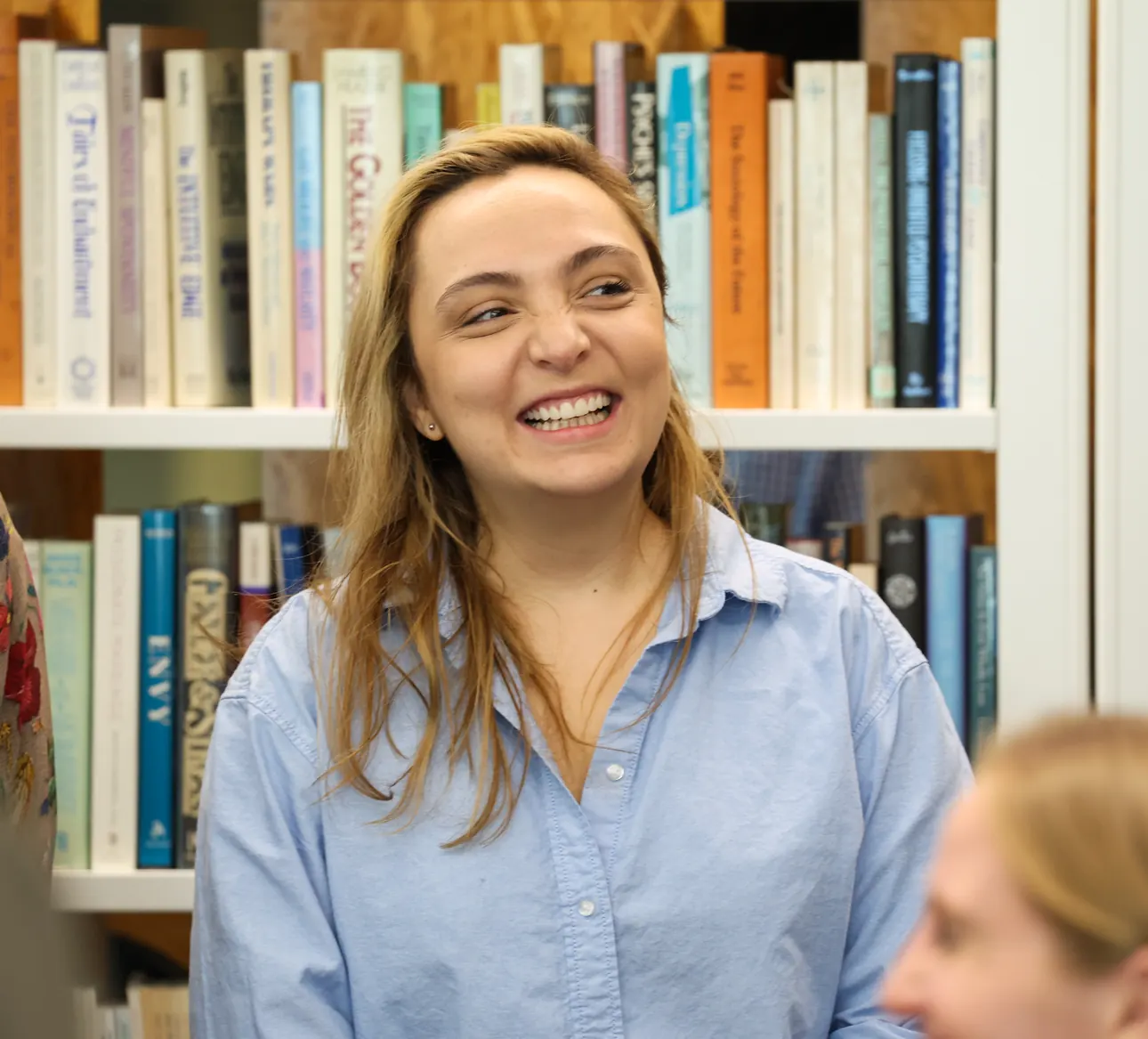 A participant smiles in front of the bookshelves at a Meridian Transformative Learning Lab