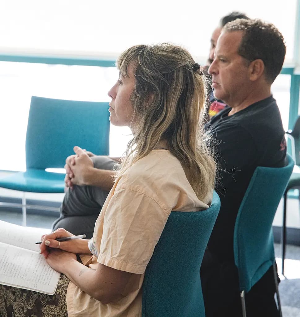 Two men and a woman smiling and having a conversation at a networking event