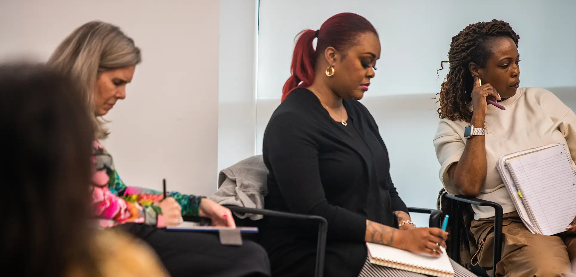 Two students take notes during a class discussion
