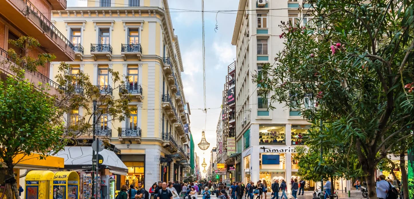 A busy pedestrian street lined with trees and ornate buildings