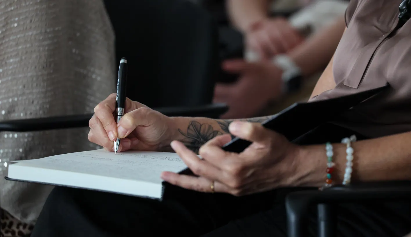 A participant takes notes in a notebook at a Meridian Transformative Learning Lab