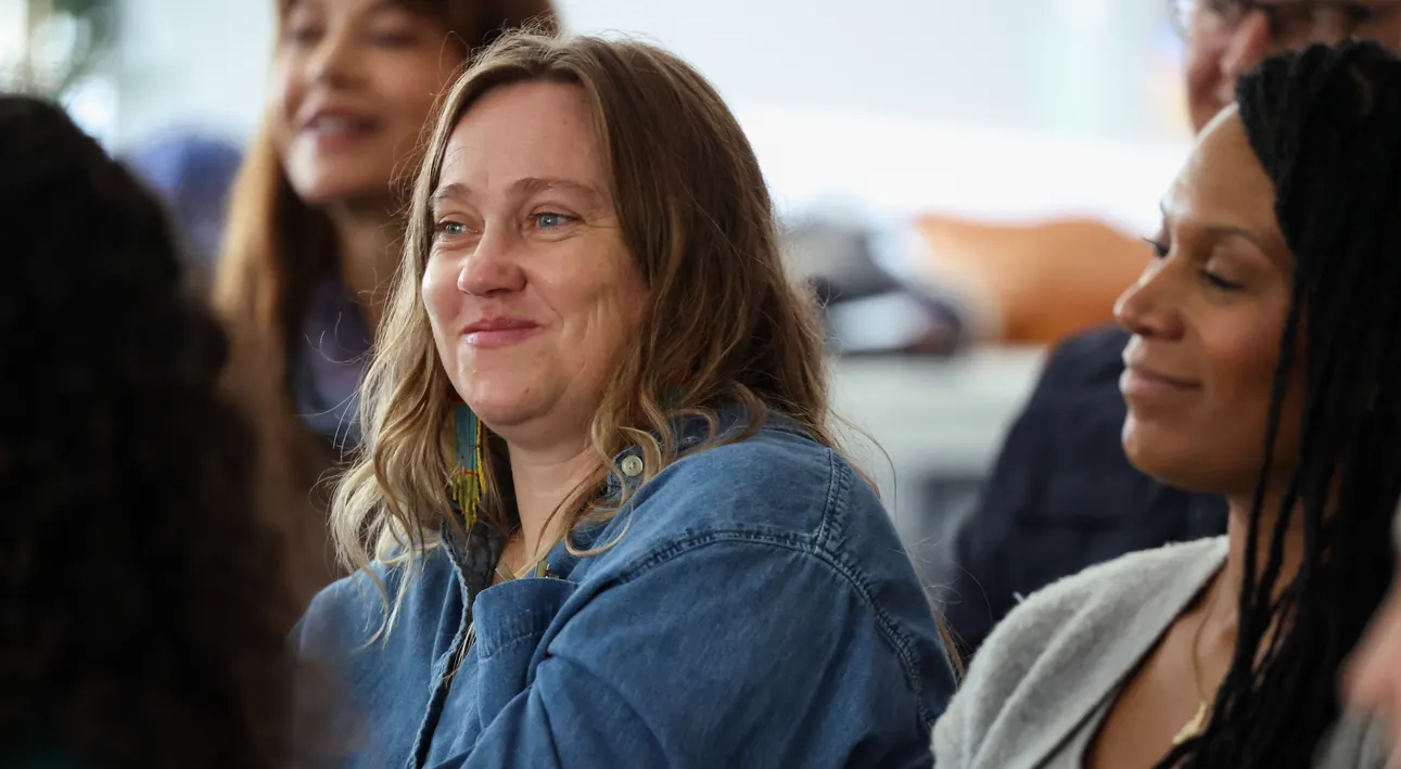 A participant smiles while listening at a Meridian Transformative Learning Lab