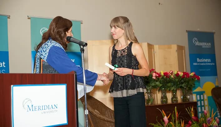 Graduate receiving a certificate during a Meridian University ceremony