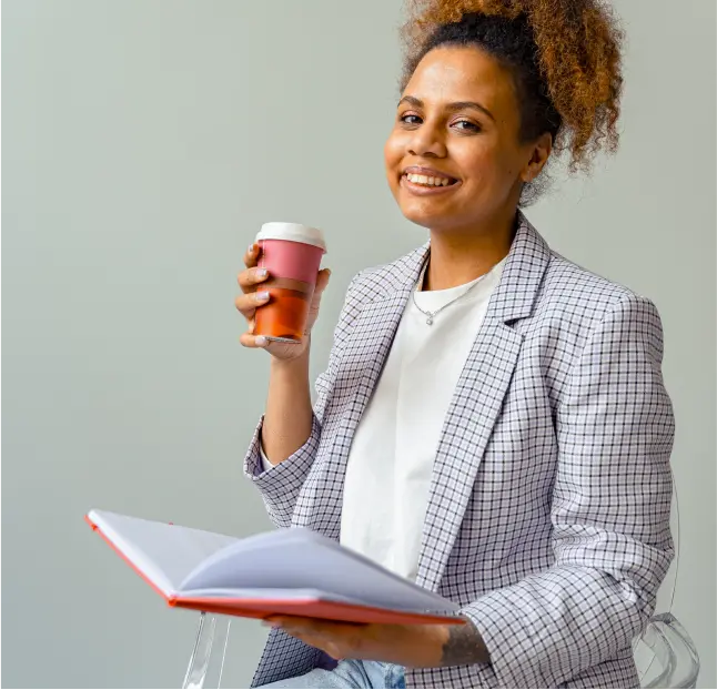 a young professional woman smiles and drinks coffee