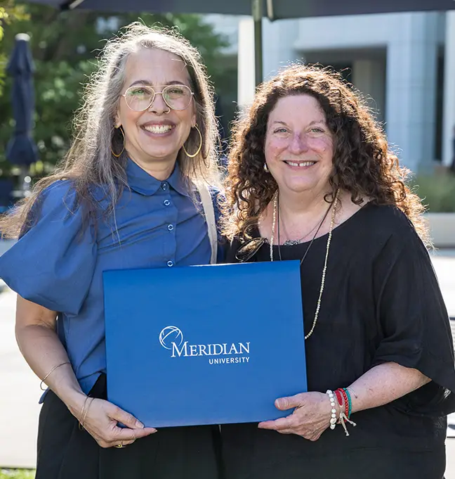 Two graduates with their Meridian diplomas at the Los Angeles Campus
