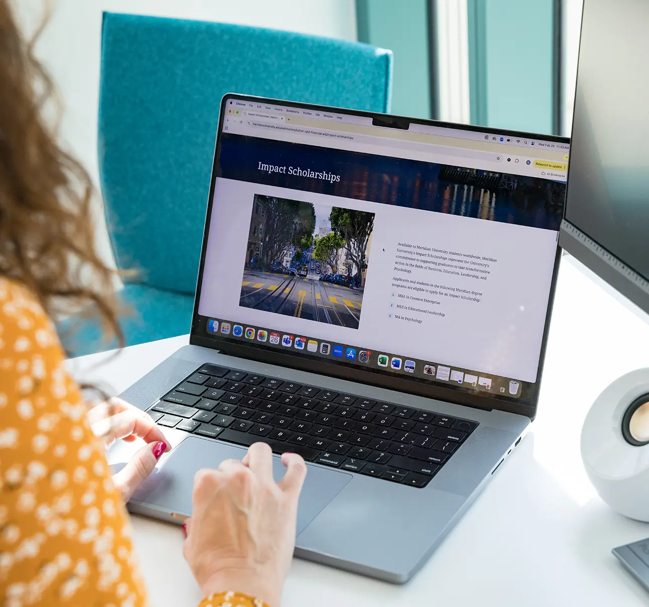 young woman sits behind laptop and book doin research in library