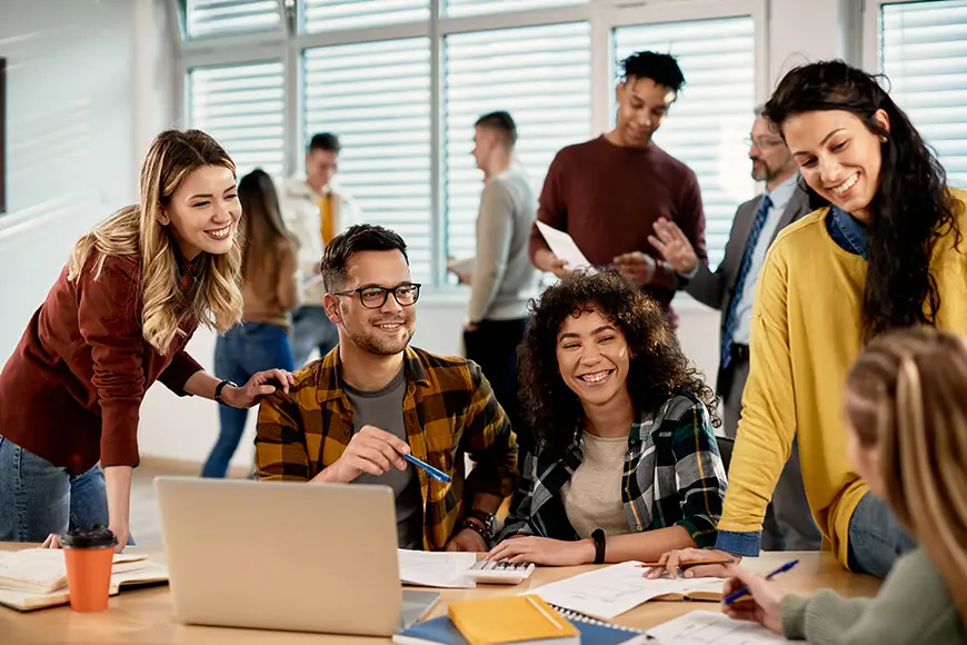 A diverse group of students huddled around a desk discussing an assignment