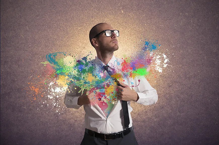 A man taking a sturdy stance holds open the chest portion of his button-up shirt. Colorful designs emerge from his chest, symbolizing creativity.