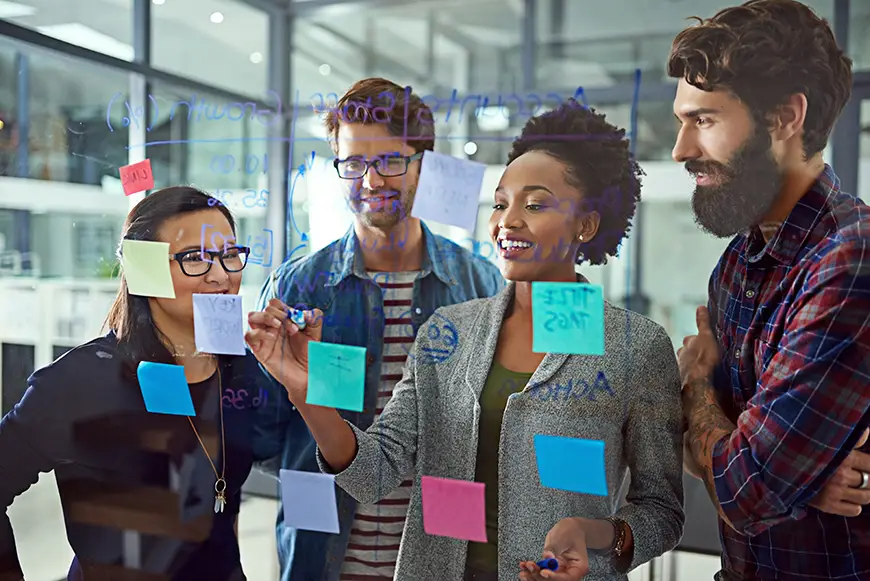 Four businesspersons develop a strategic plan on a transparent board