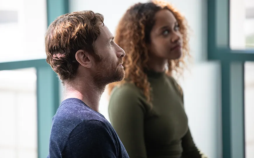 Two people attentively listening in a bright room.