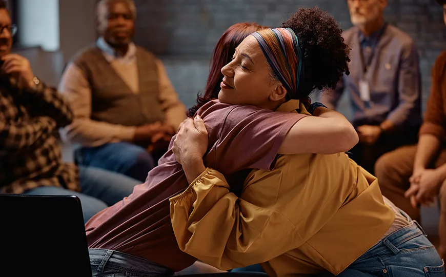 Two people embrace during a counseling group session.