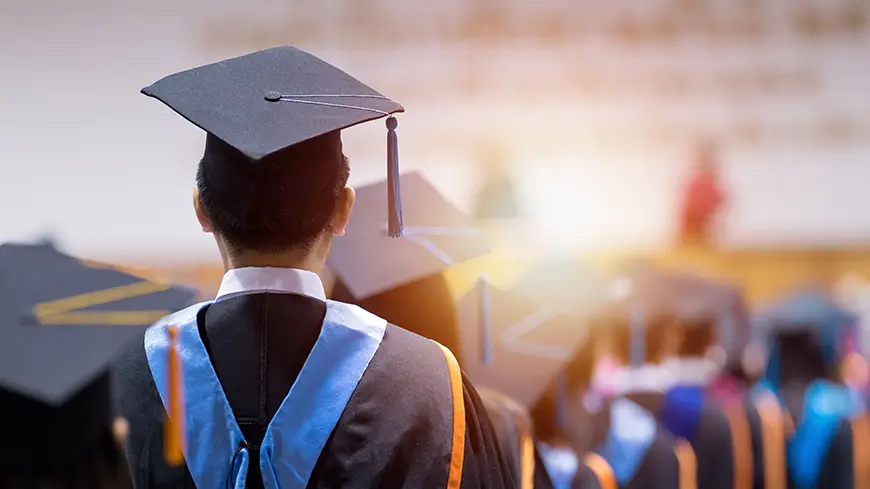 Rear view of a graduate in cap and gown at a commencement ceremony, symbolizing the successful completion of a PsyD program