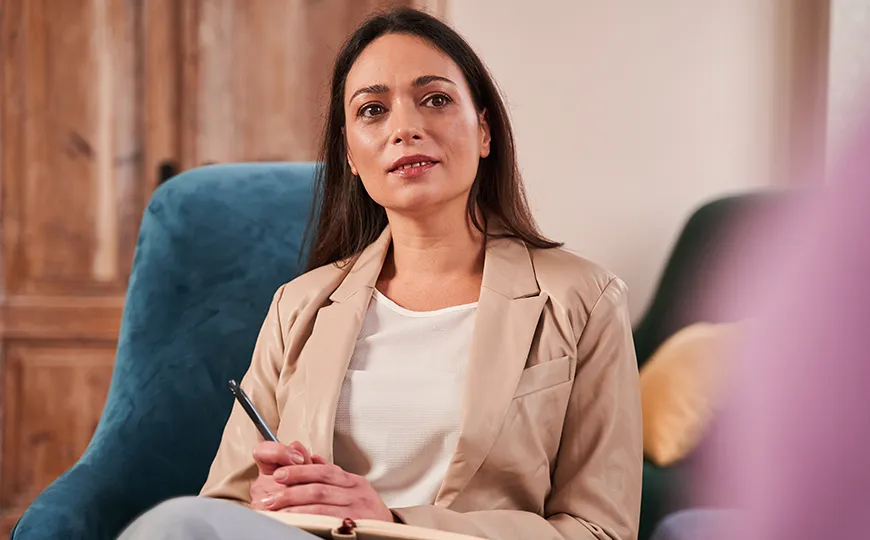 A therapist attentively listens to a client during a counseling session in a calm, well-lit office.