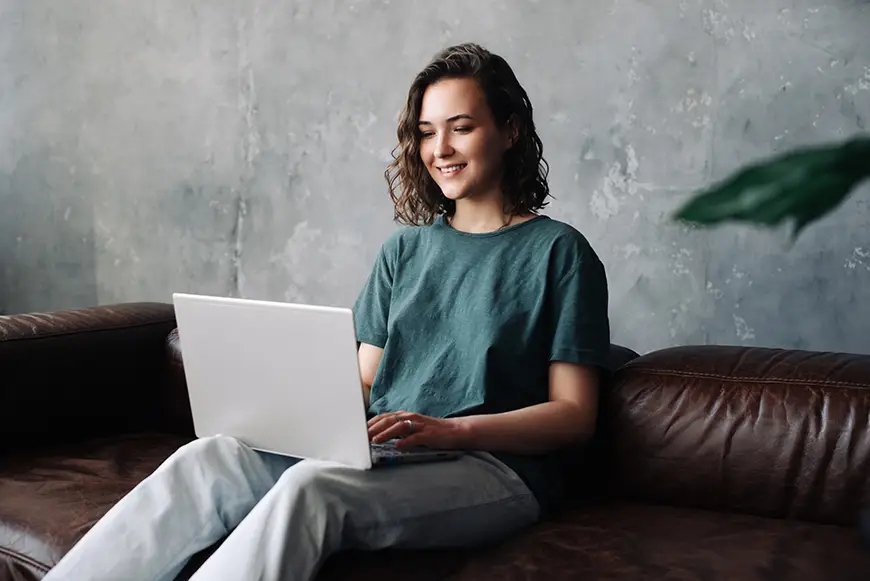 A young woman sitting on a sofa working on a laptop