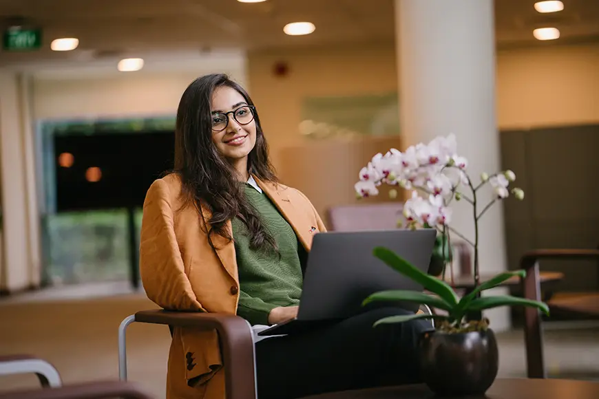An MBA candidate works on a laptop in a chair