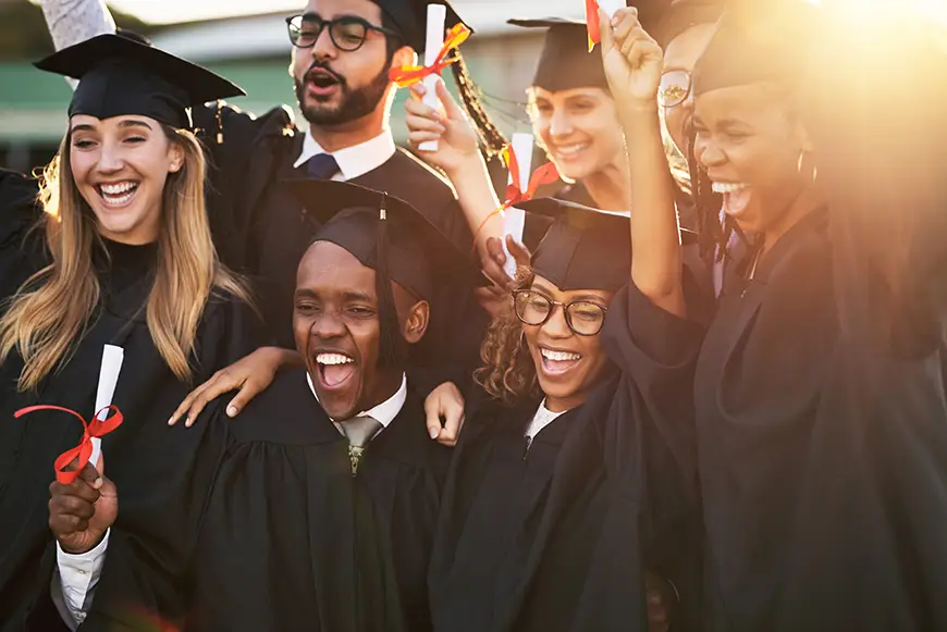 Joyful PsyD graduates celebrating their achievements with laughter and raised diplomas
