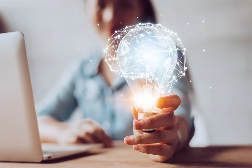 A woman holds a lightbulb that is surrounded by a holographic representation of interconnected white dots.