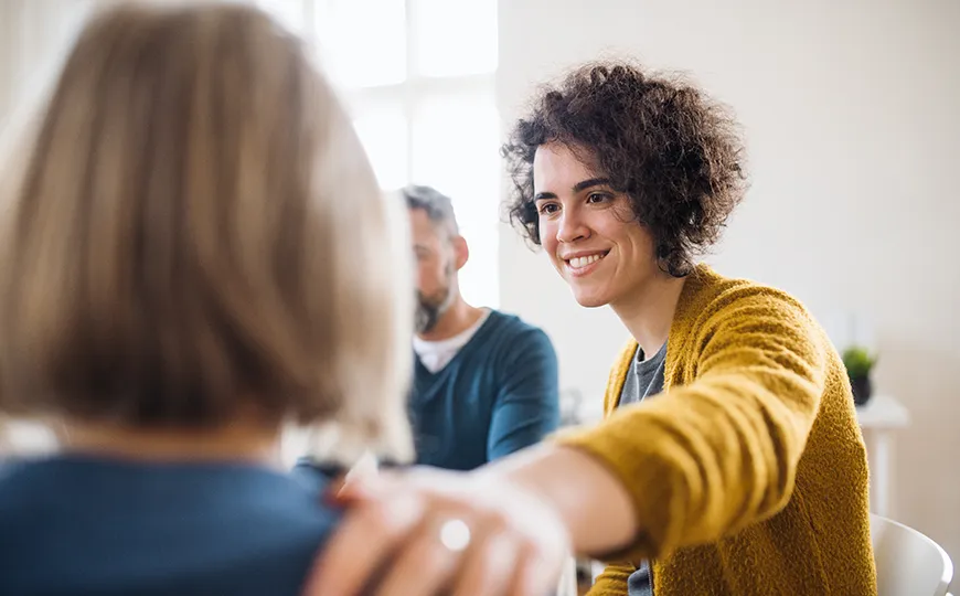 Smiling therapist offering support during a group counseling session.