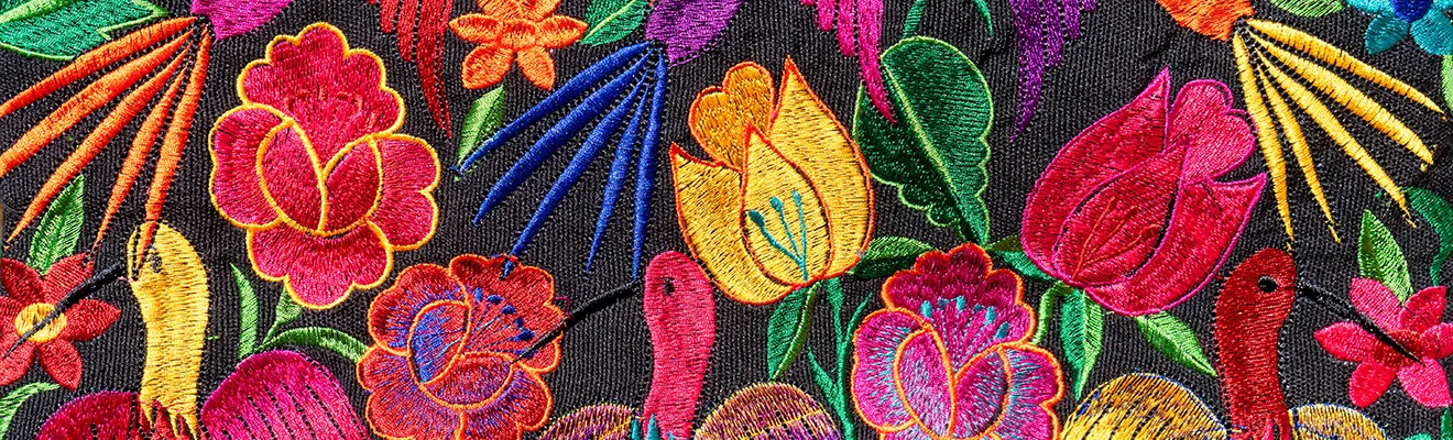 Close-up of bright floral embroidery on black cloth: roses, tulips and birds stitched in pink, yellow, blue and green thread