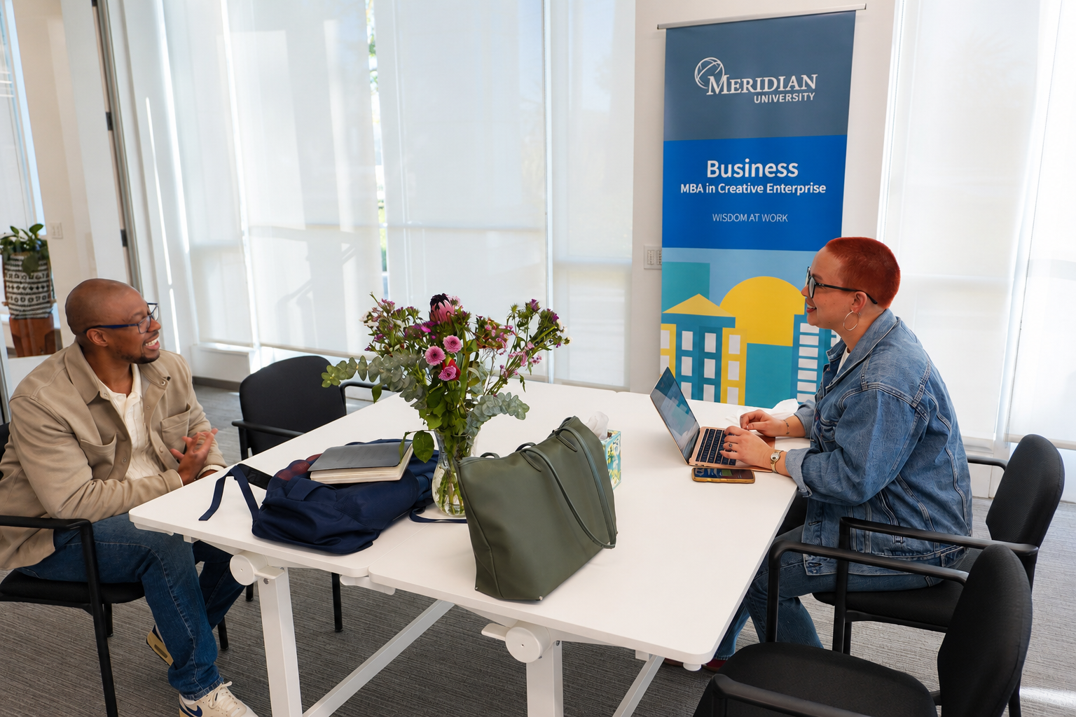 Two people sitting at a table talking at Meridian University campus